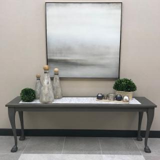 A stylish table adorned with decorative elements and modern artwork above it.