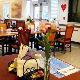 A cozy restaurant dining area with neatly arranged tables and chairs, decorated with fresh flowers.