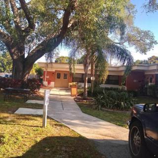 A welcoming suburban home with a well-maintained front yard and a driveway under a large tree.