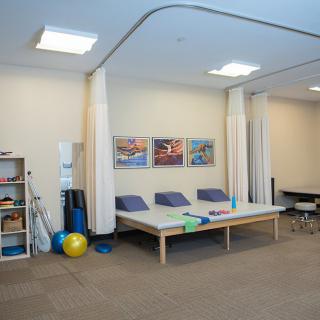 A physical therapy room equipped with exercise balls, foam rollers, and therapy tables.