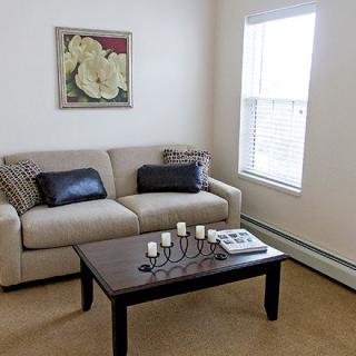 A cozy living room with a sofa and coffee table, decorated with a candle holder and wall art.
