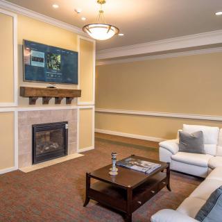 A modern living room with a fireplace and mounted television, featuring comfortable seating and stylish decor.