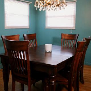 A cozy dining room with a wooden table and chairs, illuminated by a chandelier.