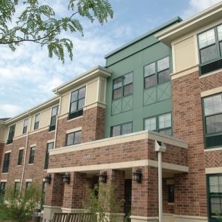 A modern apartment building with a brick facade and multiple windows.