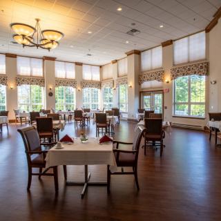 A spacious and elegant dining room with neatly arranged tables and large windows.