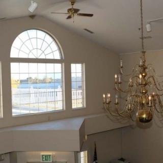 A bright interior space featuring a large chandelier and expansive arched windows.