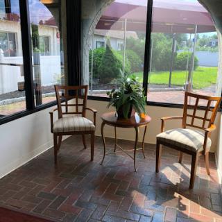 A bright and inviting seating area with two chairs and a small table, surrounded by large windows that let in natural light.
