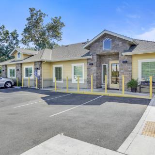 A building with a parking lot surrounded by trees, photographed during the daytime.