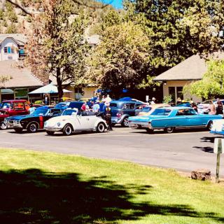 A beautiful sunny day at a classic car show with vintage vehicles lined up along the street.