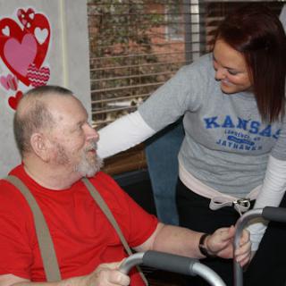 A caregiver engages with an elderly man, sharing a warm moment of support and interaction.