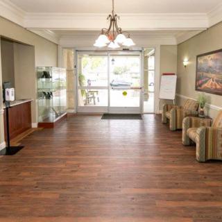 A spacious lobby area with wooden flooring, comfortable seating, and a bright entrance.