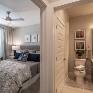 A modern bedroom with an attached bathroom, featuring stylish decor and neutral tones.
