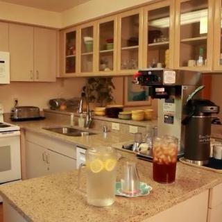 A cozy kitchen with a coffee maker, lemonade, and iced tea on the countertop.