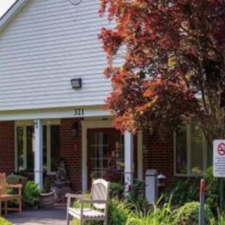 A cozy house with a front garden and bench under a red-leaved tree.