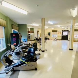 A spacious gym with various exercise equipment and bright lighting.