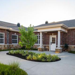 A brick building with a landscaped courtyard and garden at the entrance.