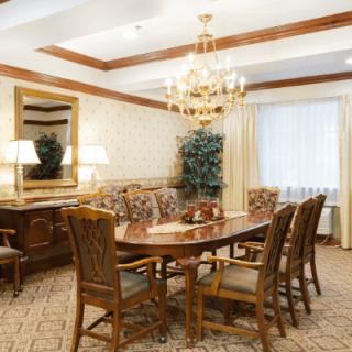 An elegant dining room with a large table, chairs, and a chandelier.