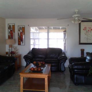 A cozy living room with leather sofas and a wooden coffee table, adorned with artwork and a ceiling fan.