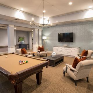 A spacious game room featuring a pool table, comfortable seating, and a wall-mounted television.
