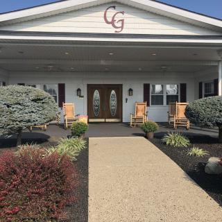 Entrance of a building with a pathway, landscaping, and porch seating.