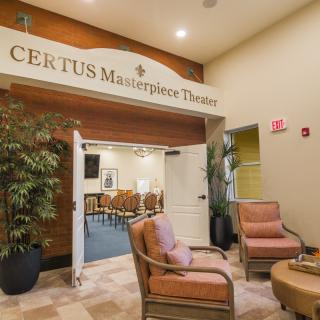 The inviting entrance of CERTUS Masterpiece Theater features comfortable seating and decorative plants.