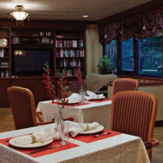 A cozy and elegant dining area with neatly set tables and a bookshelf in the background.