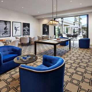 A modern lounge area featuring vibrant blue seating, stylish geometric carpeting, and framed artwork, with ample natural light.
