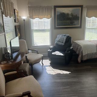 A cozy room featuring a bed, recliner, and comfortable seating area with natural light.
