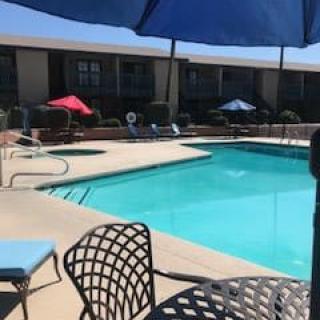A sunny day at an outdoor swimming pool with lounge chairs and colorful umbrellas.