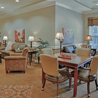A cozy and elegantly designed living room featuring comfortable seating, a table with chairs, warm lighting, and decorative artwork on the walls.