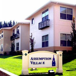 An image of the Assumption Village apartment complex with a clear sign in front.