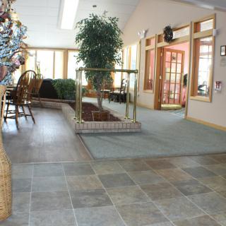 A bright and spacious interior lobby area with plants and tile flooring.