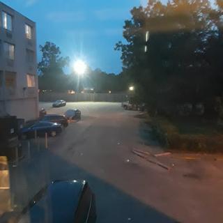 A quiet evening scene in a parking lot illuminated by street lights.