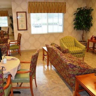 A cozy seating area with patterned chairs and sofas, a table set for dining, and a large window.