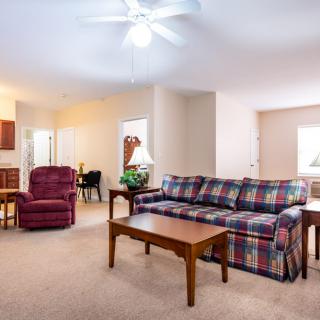 A cozy living room with a plaid sofa, an armchair, and wooden furniture.