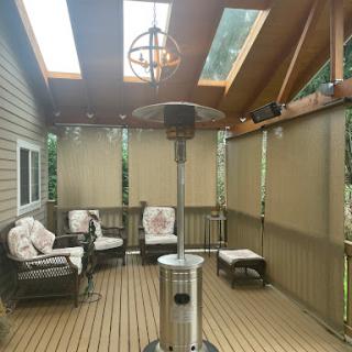 A cozy outdoor patio featuring comfortable seating, a patio heater, and natural light from skylights.