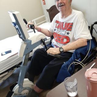 An elderly person engaged in a cycling exercise while seated in a wheelchair.