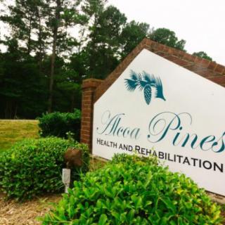 Sign for Aspen Pines Health and Rehabilitation surrounded by greenery.