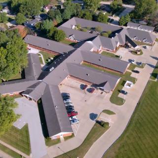 An aerial view of a building complex surrounded by trees and parking spaces.