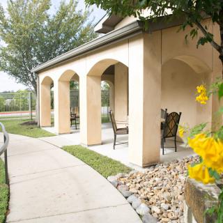 A charming patio with arches and seating, surrounded by a garden path.
