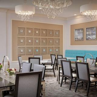An elegantly designed dining room featuring chandeliers, framed artwork, and sophisticated furniture.