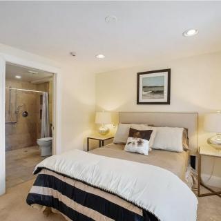 A cozy, well-lit bedroom with a comfortable bed, decorated with neutral tones and featuring modern furniture.