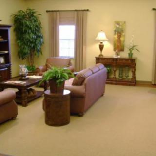 A neatly arranged living room with comfortable sofas, a central table, and decorative plants.