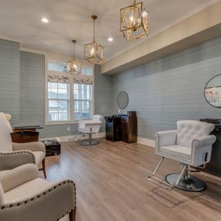 A stylish and elegant salon interior with comfortable chairs, modern lighting, and a large window.
