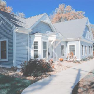 A charming residential house with blue siding, a walkway, and landscaped front yard.