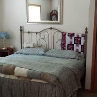 A cozy bedroom with a neatly made bed, decorative pillows, and a large mirror on the wall.