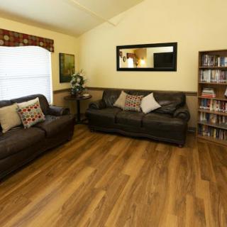 A cozy living room featuring comfortable sofas, a warm wooden floor, and decorative elements.