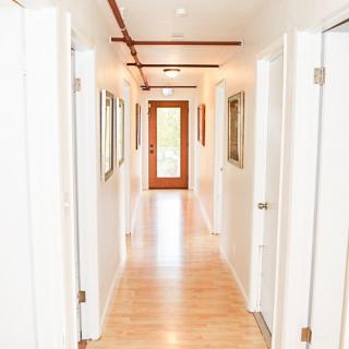 A brightly lit modern hallway with wooden flooring and multiple doors.