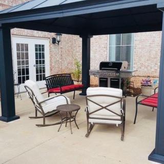 A cozy outdoor patio setup with a pergola, chairs, a table, and a grill.