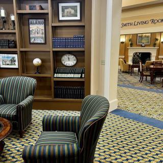 A cozy library interior featuring bookshelves, comfortable chairs, and a clock.
